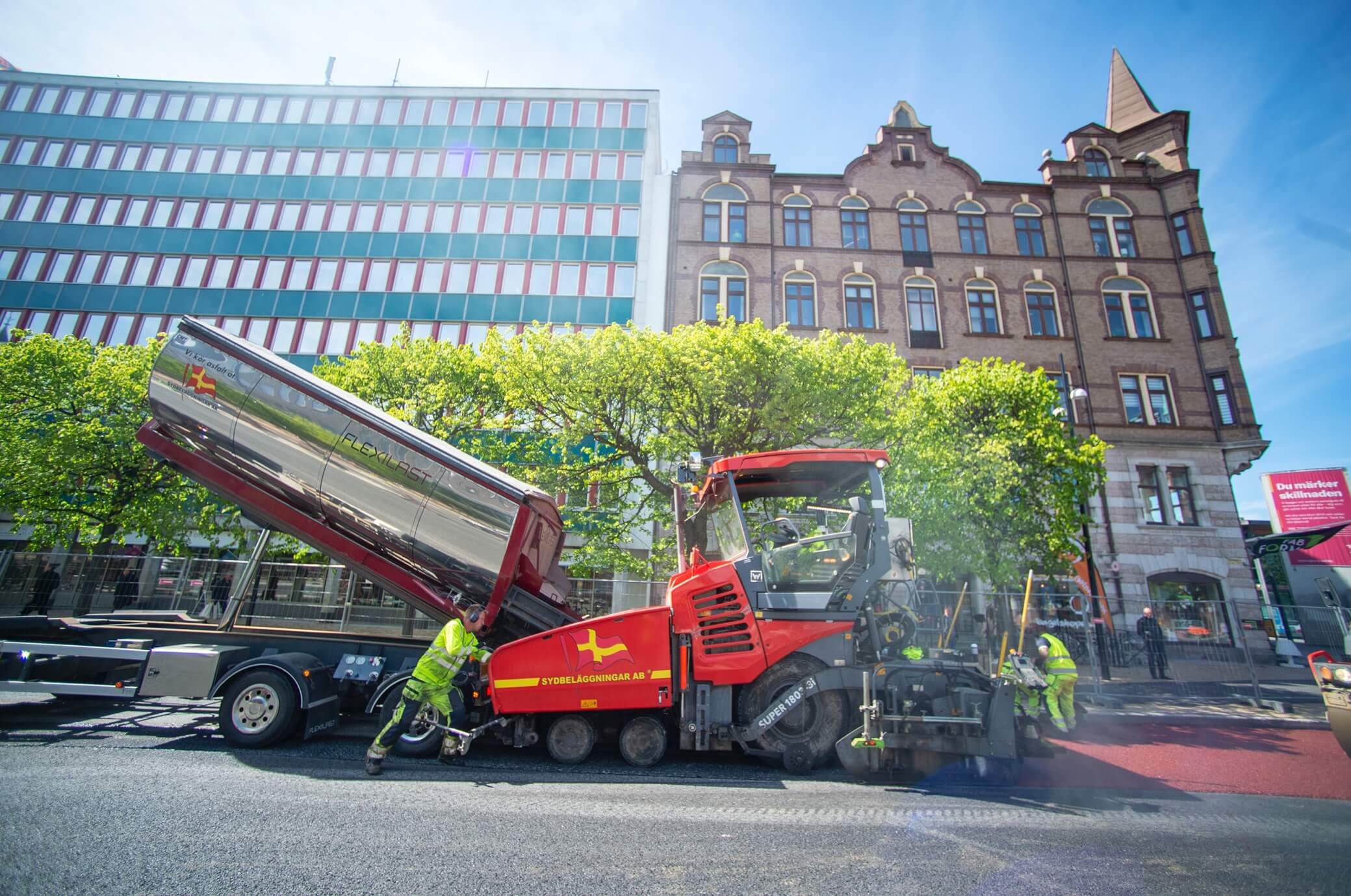 Anställda lägger asfalt med sin asfaltsläggare