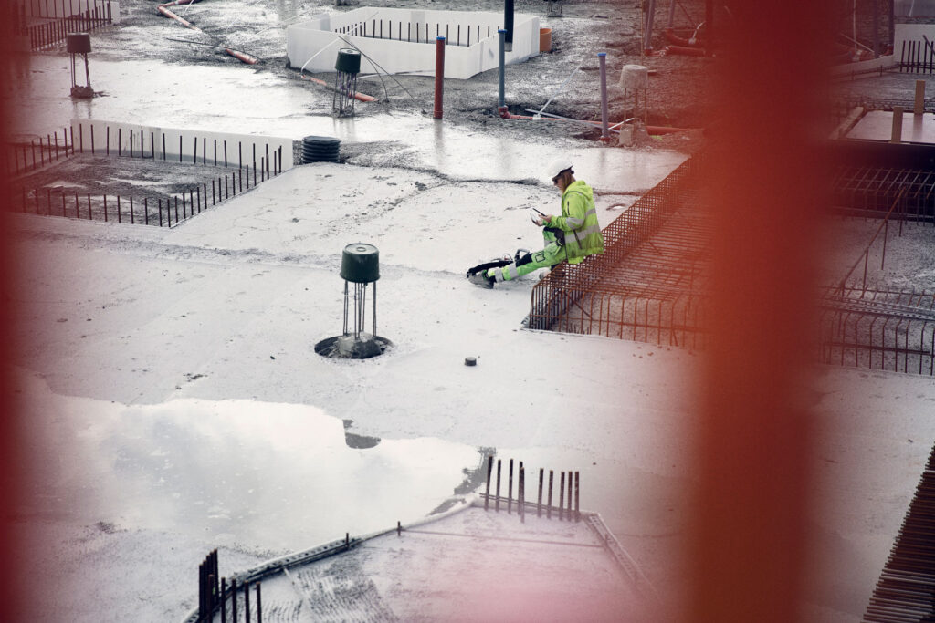 byggarbetare läser meddelande via app på byggarbetsplats