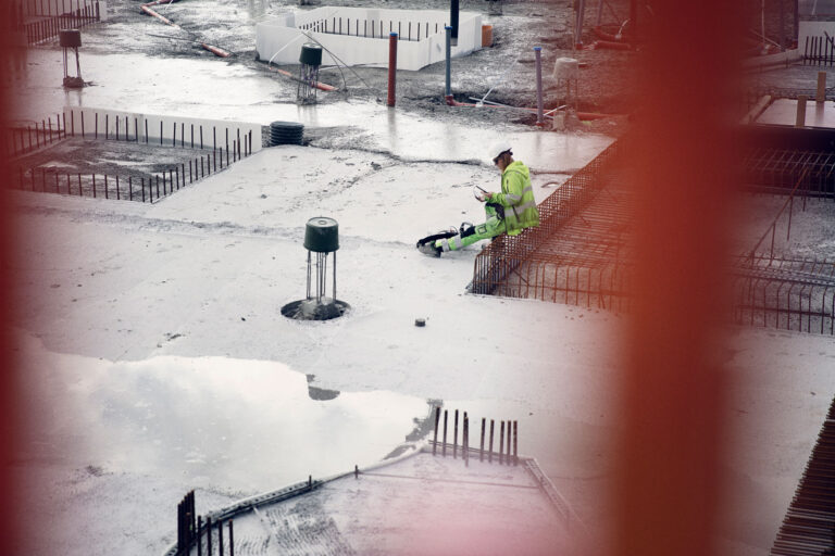 byggarbetare läser meddelande via app på byggarbetsplats